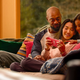 A family gathers around a mom, who is playing a pink Nintendo Switch lite.